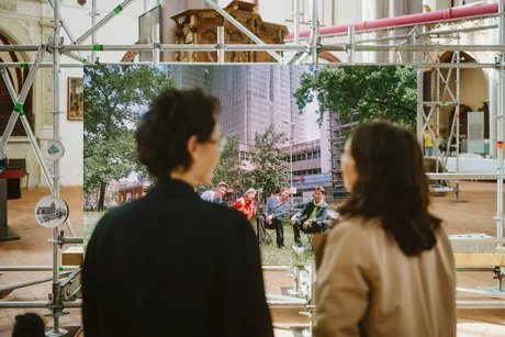 Blick über die Schulter zweiter Besucherinnen auf einen Film-Monitor im Museum