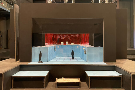 Bühnenbildmodell, Querschnitt eines ca. 2 Meter tiefen Schwimmbeckens mit hellblauen Fließen, am hinteren Beckenrand ein rötlicher Vorhang