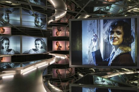 Blick in die ständige Ausstellung: Spiegelsaal Film mit Projektionen aus verschiedenen Filmen, die sich in den Spiegeln wiederholen. Auf den Bildschirmen sind verschiedene Schauspielerinnen zu sehen.