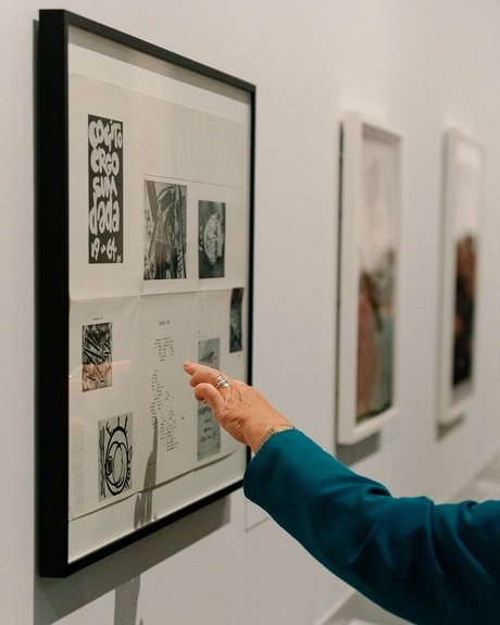 Eine Hand deutet auf ein Detail in einer gerahmten Collage von Raoul Hausmann, die an der Wand hängt.
