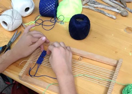Auf einem Webrahmen entsteht ein buntes Schmuckband.