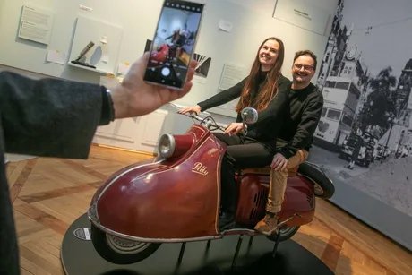 Zwei Besucher:innen beim "Foto-Shooting" auf dem Motorroller.