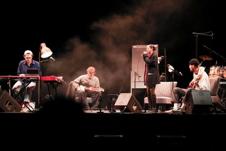 Eine vierköpfige Band bestehend aus Keyboarder, Gitarrist, Bassist und Sängerin spielt auf einer Bühne. Eine vierköpfige Band bestehend aus Keyboarder, Gitarrist, Bassist und Sängerin spielt auf einer Bühne.
