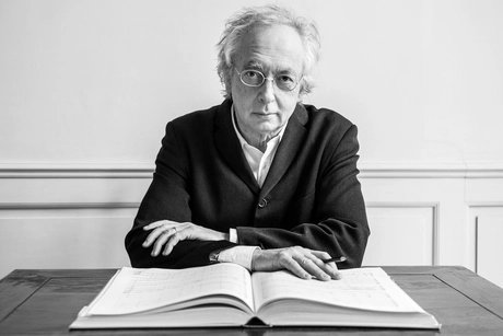 Dirigent Philippe Herreweghe sitzt vor einer Partitur und schaut in die Kamera.