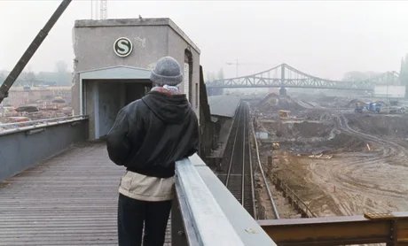 Mann auf Brücke mit S-Bahn-Eingang blickt über eine Baustelle auf eine Brücke