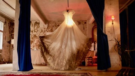 Ein Brautkleid hängt als Leuchte von der Deckenwand