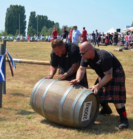 Zwei Männer im Kilt rollen ein 200 Kilogramm Fass