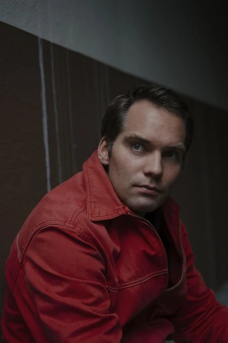 Portrait von Simon Strauß: seitliche Schulteraufnahme eines Mannes in roter Jacke