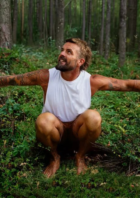 Xavier Rudd in einem Wald hockend