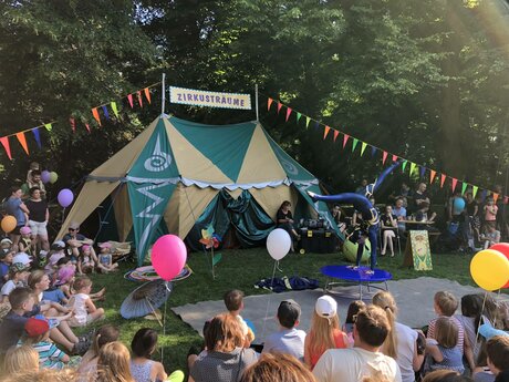 Kinderzirkus "Zirkusträume" - Akrobat, zuschauende Kinder und Zelt beim Kunstfest