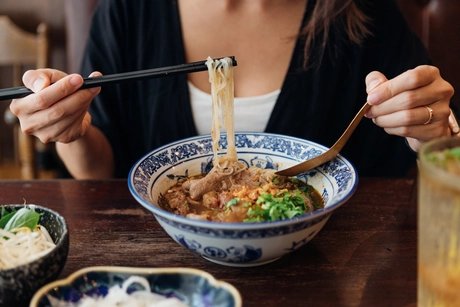 Eine Frau isst eine Nudelsuppe