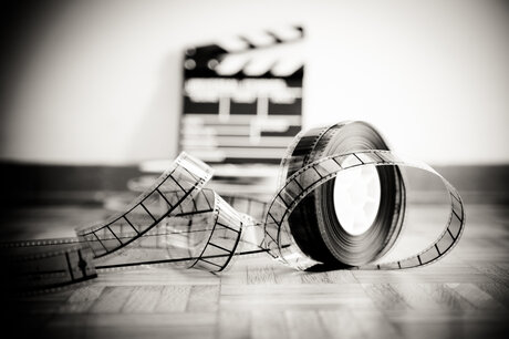 Close-Up Of Rolled Film Reel Against Slate On Wooden Floor By Wall