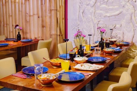 Amrit Restaurant – Gedeckte Tafel vor Bambuswand und Steinrelief
