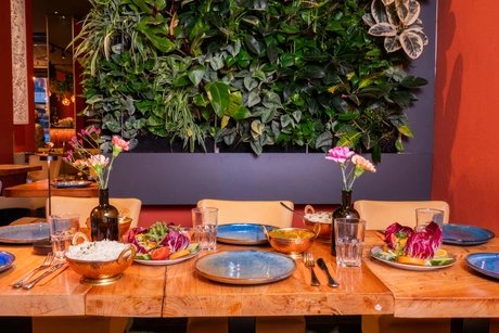 Amrit Restaurant – Gedeckter Tisch mit Pflanzenwand