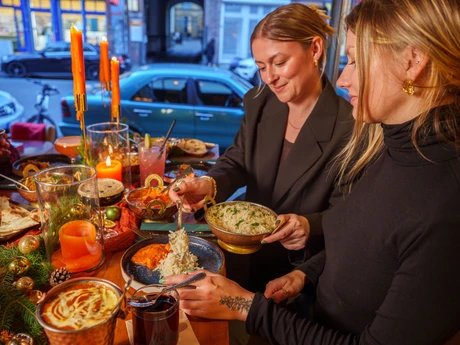 Amrit Restaurant – Zwei Frauen servieren Reis an weihnachtlicher Tafel