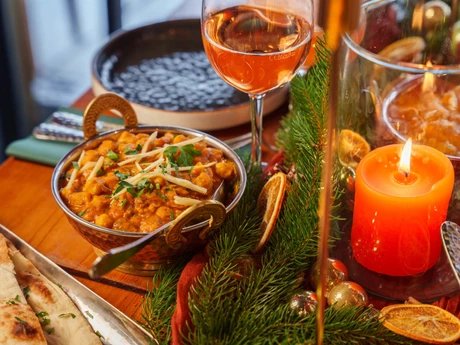 Amrit Restaurant – Curry-Gericht mit Weinglas und Kerzenlicht