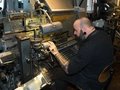 Ein Mann arbeitet an einer großen, schwarzen Setzmaschine.