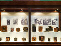 Eine große Vitrine aus dunklem Holz zeigt verschiedene historische Kameras mit Holzgehäuse. Im Hintergrund hängen einige Schwarzweißaufnahmen.