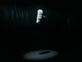 Ein einzelnes Mikrofon mit grauem Fellüberzug hängt im Spotlight, der Rest der Bühne bleibt dunkel.