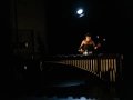 Eine Musikerin spielt mit Schlegeln auf einem Marimbaphon, beleuchtet von einem einzelnen Scheinwerfer.