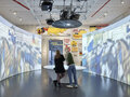 Besucher:innen der Ausstellung BERLIN GLOBAL beim Rad der Geschichte, einem Display-Tisch, im Raum Revolution