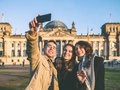 three young people taking selfie in front of Berlin Reichstag