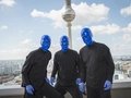 Die BLUE MAN GROUP posiert vor dem Fernsehturm bei strahlend blauem Himmel.