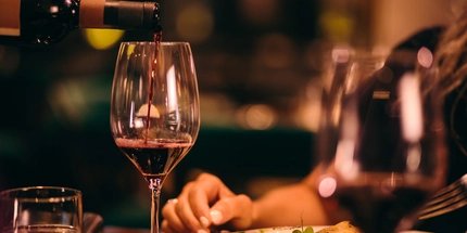 Nahaufnahme eines Sommeliers beim Servieren von Rotwein in einem gehobenen Restaurant