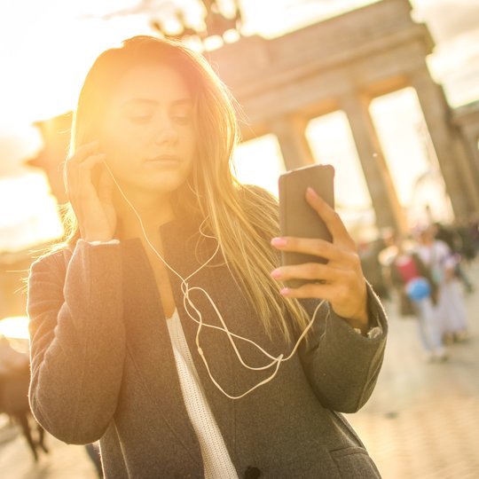 Young woman listening to audio tour at Brandenburg Gate.