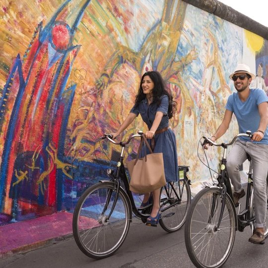 Pärchen auf Fahrrädern an der East Side Gallery