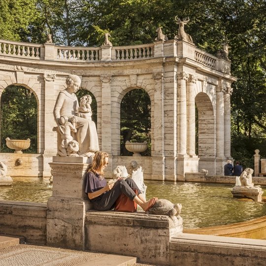 Una donna legge alla fontana fiabesca del Volkspark Friedrichshain di Berlino