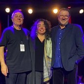 Drei Musiker:innen stehen nebeneinander und lächeln