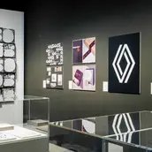 Blick auf an Wänden gehängte Plakate und Vitrinen mit Objekten im Vordergrund