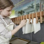 Ein Kind hängt Papier zum Trocknen auf.