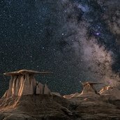 Die Oberfläche eines Planeten mit der Milchstraße im Hintergrund.