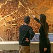 Besucherin und Besucher vor einem Stadtmodell mit Medienstation