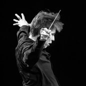 Dirigent Esa-Pekka Salonen breitet die Arme vor dem Orchester aus.