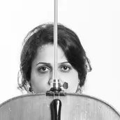 Schwarzweiß Fotografie der Cellistin: Die Hälfte ihres Gesichts wird von ihrem umgekehrten Cello verdeckt.