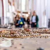 Modell der mittelalterlichen Stadt Berlin im Museum Nikolaikirche, im Hintergrund unscharf Besucher und das Innere des Kirchenschiffs