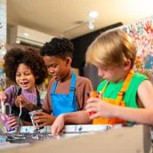 Fröhliche Kinder gestalten mit Farbe in einem Werkraum.