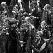 Musiker:innen spielen ihre Instrumente. Durchsichtige Tücher liegen über ihren Köpfen.