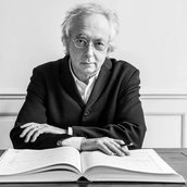 Dirigent Philippe Herreweghe sitzt vor einer Partitur und schaut in die Kamera.