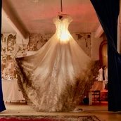 Ein Brautkleid hängt als Leuchte von der Deckenwand