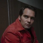 Portrait von Simon Strauß: seitliche Schulteraufnahme eines Mannes in roter Jacke