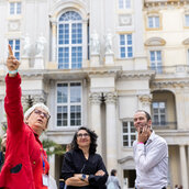 Eine Stadtführerin beschreibt den Gästen die Fassade des Humboldt Forums.