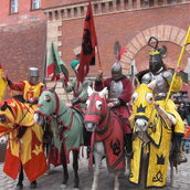 Vier Ritter auf Pferden halten jeweils ein Banner in ihren Händen, vor der Zitadelle Spandau stehend