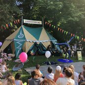 Kinderzirkus "Zirkusträume" - Akrobat, zuschauende Kinder und Zelt beim Kunstfest