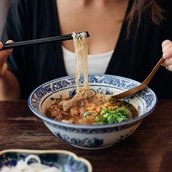 Eine Frau isst eine Nudelsuppe