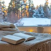 Ein aufgeschlagenes Buch am Fenster liegend vor winterlicher Kulisse