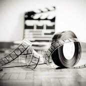 Close-Up Of Rolled Film Reel Against Slate On Wooden Floor By Wall